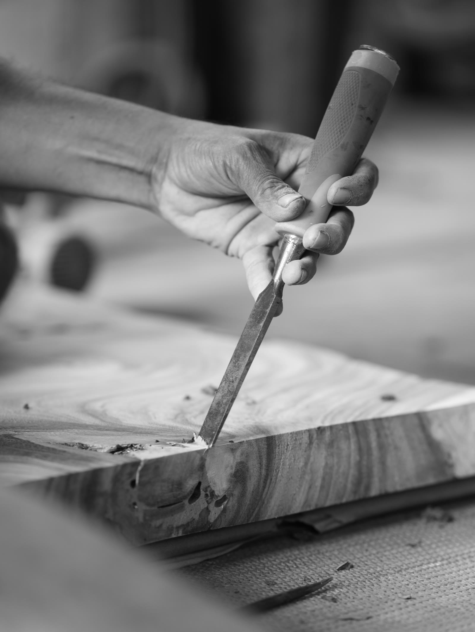 A craftsperson carving a solid piece of timber by hand